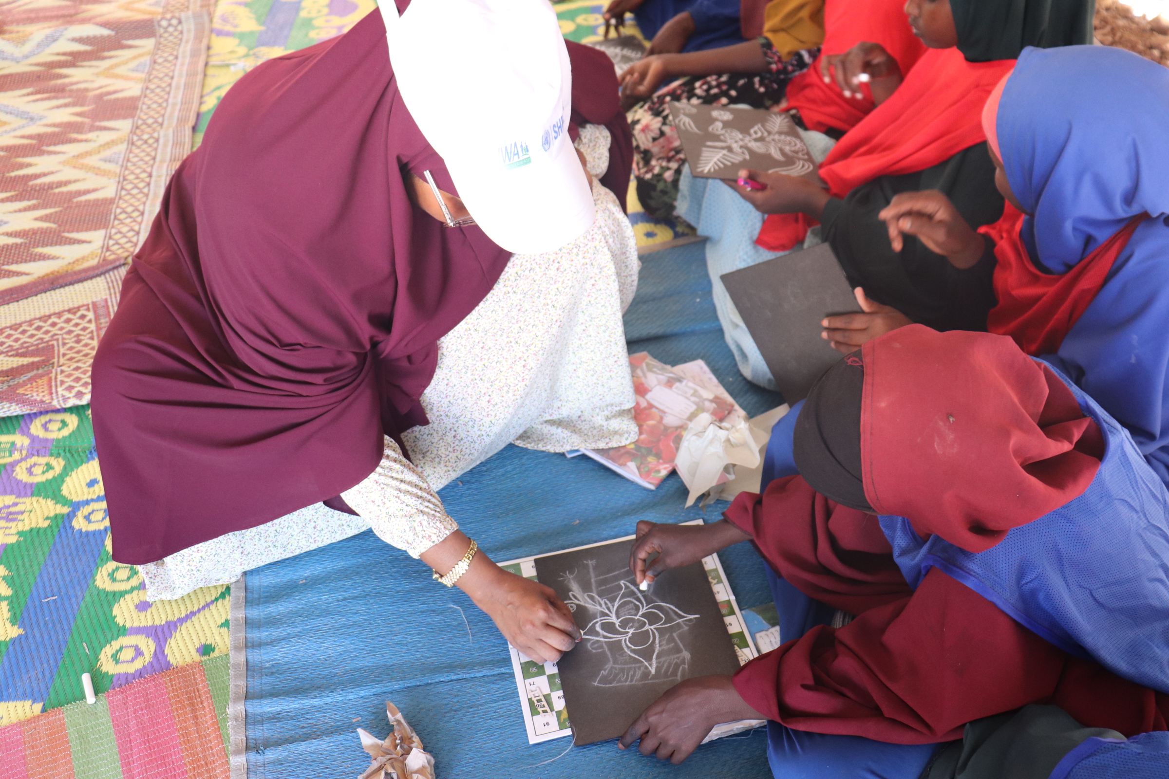 HIWA facilitator supporting children in a drawing activity