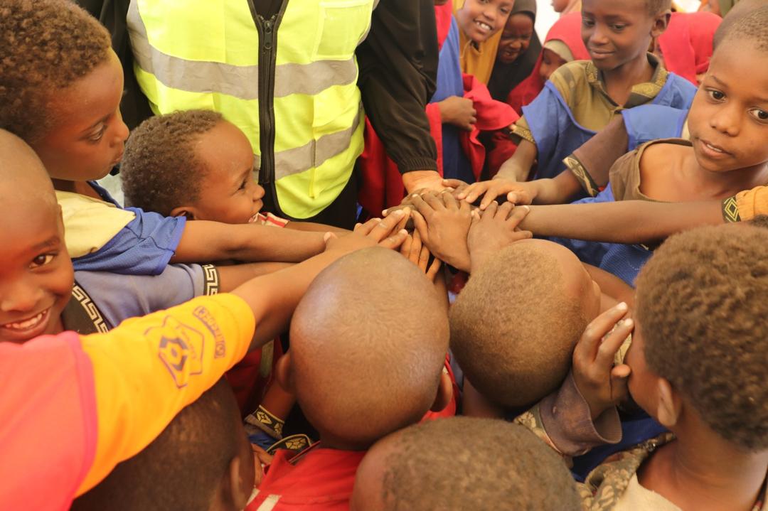 Children and a facilitator joining hands during a group activity