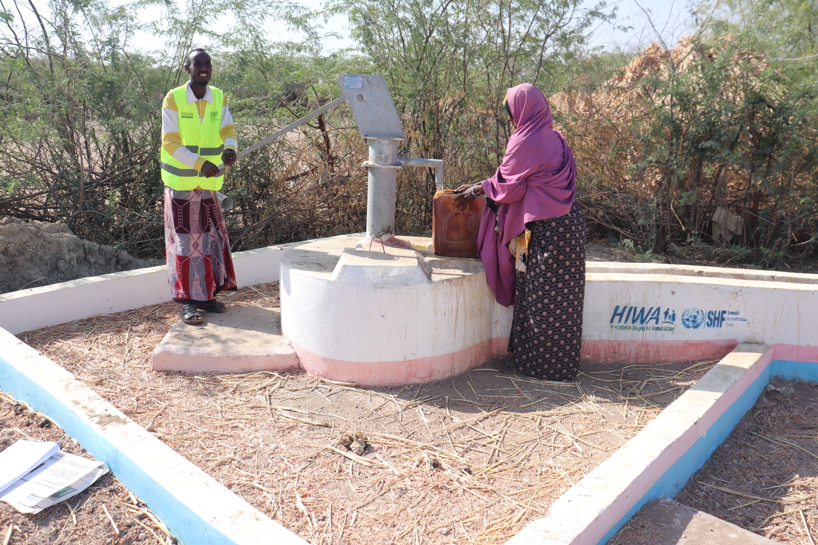 HIWA worker and community member beside a water point